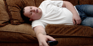 Man asleep on the couch, with TV remote control firmly in hand. Man asleep on the couch, with TV remote control firmly in hand.
